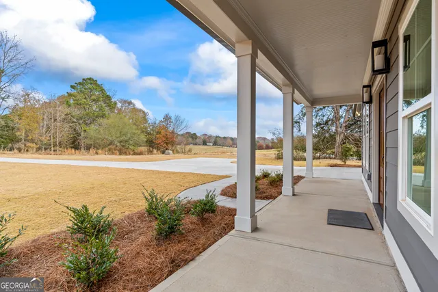 a view of an empty room with wooden floor and a kitchen