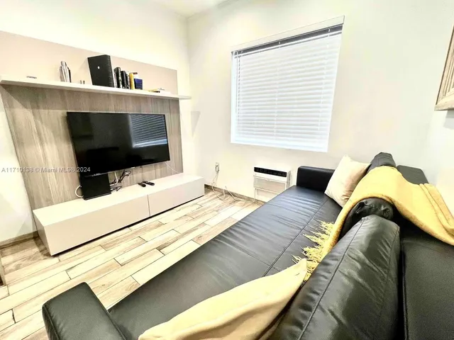 a living room with a bed furniture and flat screen tv