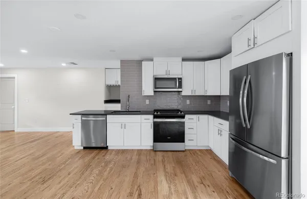 a kitchen with granite countertop a refrigerator stove and sink