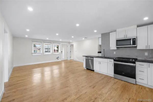 a large kitchen with stainless steel appliances granite countertop a stove a sink and a microwave