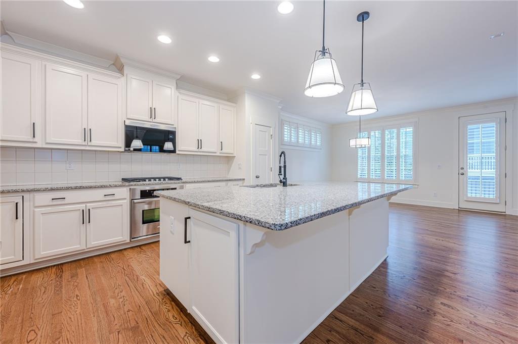 247 Fowler Street Woodstock, GA 30188 - Photo 15 of 72 a large kitchen with granite countertop a stove a sink a center island and wooden floor