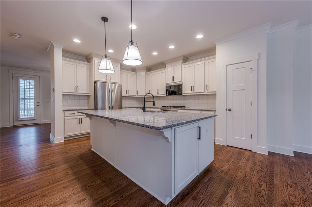 247 Fowler Street Woodstock, GA 30188 - Photo 16 of 72 a kitchen with kitchen island granite countertop wooden floors white cabinets and stainless steel appliances