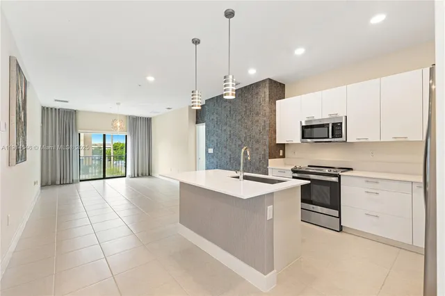 a large kitchen with stainless steel appliances granite countertop a stove a sink and a refrigerator