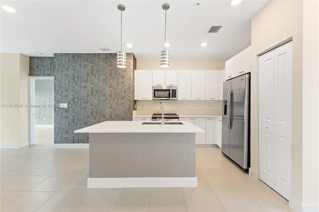 a kitchen with kitchen island a sink stainless steel appliances and cabinets
