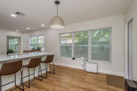 a dining room with wooden floor a chandelier a wooden table and chairs