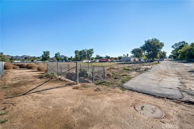 a view of a dry yard with wooden fence