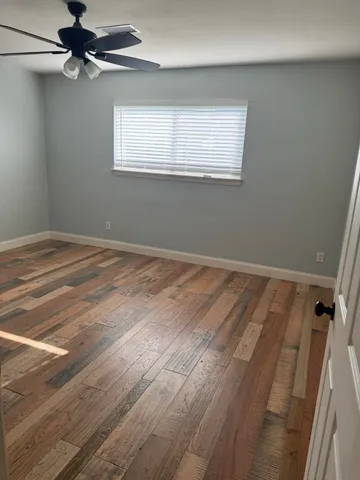 en empty room with wooden floor fan and windows