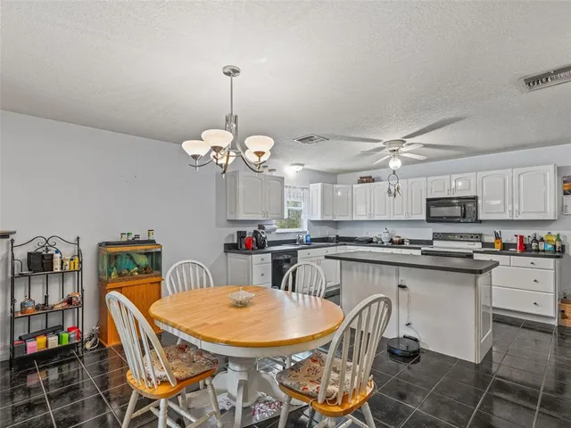 a dining room filled chandelier and kitchen view