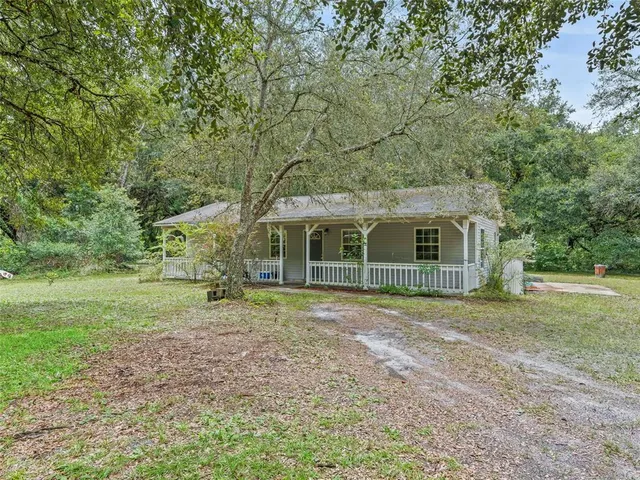 a view of a yard in front of a house with large trees