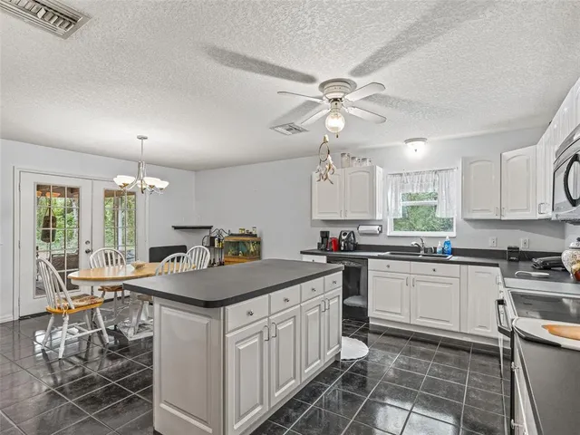a kitchen with stainless steel appliances granite countertop a sink a stove a dining table and chairs
