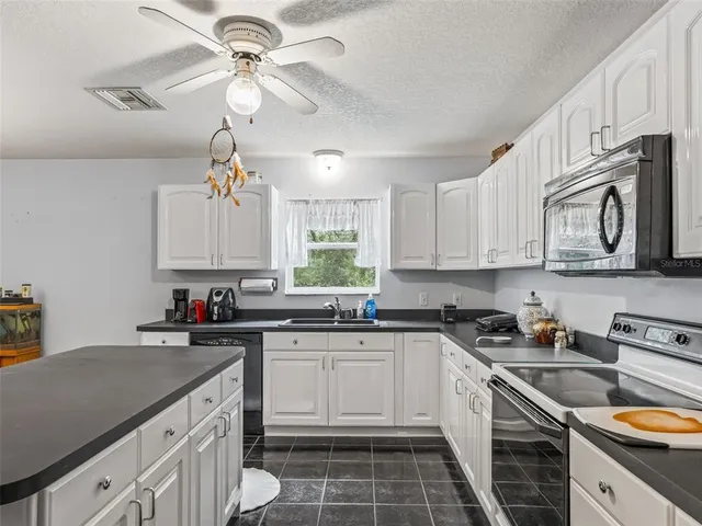 a kitchen with a sink dishwasher a stove and white cabinets