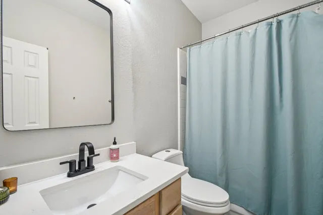 a bathroom with a sink a toilet and shower curtain