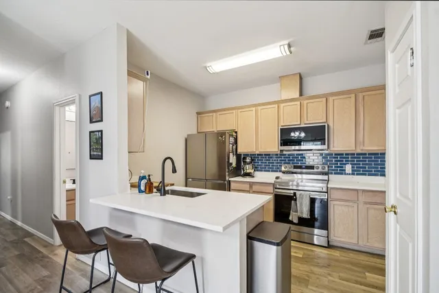 a kitchen with stainless steel appliances a sink a stove a refrigerator cabinets and a dining table