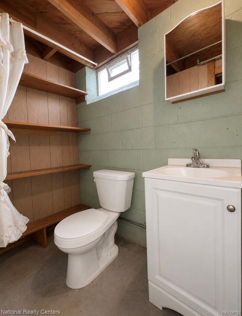 7285 Helen Street Center Line, MI 48015 - Photo 24 of 32 Compact bathroom featuring exposed wood-finish ceiling joists, concrete block walls, a white toilet, and a white vanity with an integrated sink