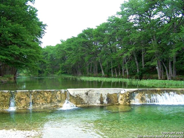 319 RiverTree N Road Rio Frio, TX 78879 - Photo 20 of 21 a view of a lake with a big yard and large trees