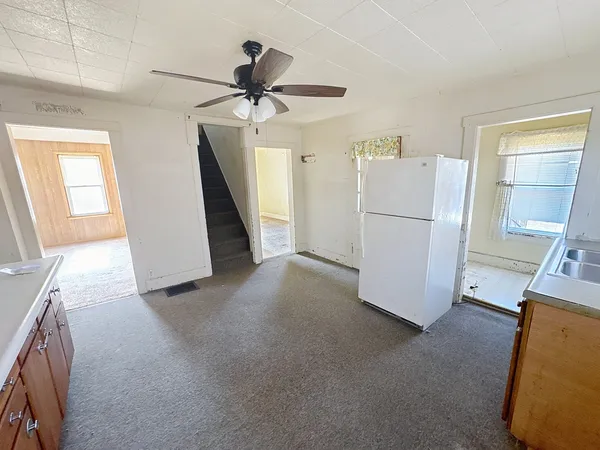 a view of a livingroom with a ceiling fan & a window