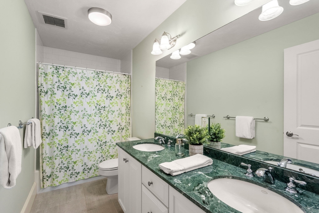 18 Maple Court, Unit 18 Needham, MA 02492 - Photo 20 of 25 a bathroom with a granite countertop sink a large mirror and a shower