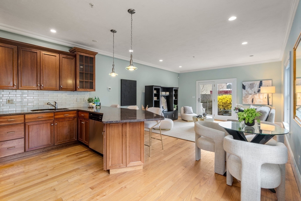 18 Maple Court, Unit 18 Needham, MA 02492 - Photo 7 of 25 a kitchen with stainless steel appliances granite countertop a refrigerator a sink dishwasher a dining table and chairs with wooden floor