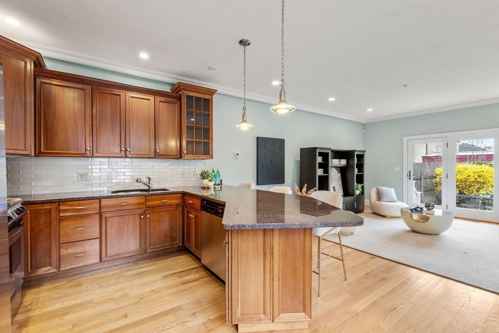 18 Maple Court, Unit 18 Needham, MA 02492 - Photo 8 of 25 a large kitchen with kitchen island granite countertop a sink a counter space and stainless steel appliances