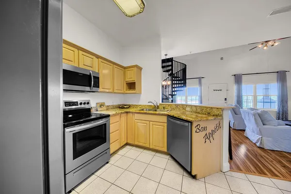 a kitchen with stainless steel appliances granite countertop a stove top oven a sink dishwasher and white cabinets with wooden floor