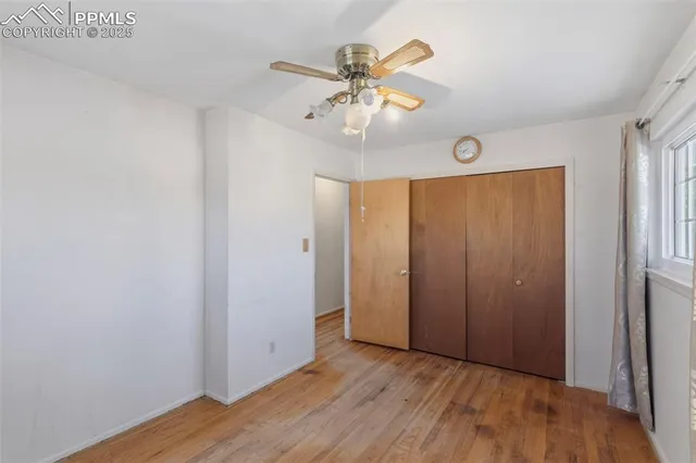 an empty room with wooden floor fan and windows