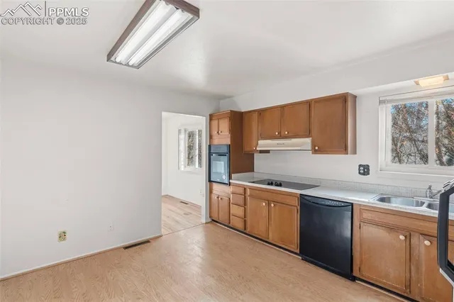 a kitchen with stainless steel appliances granite countertop a sink and cabinets with wooden floor