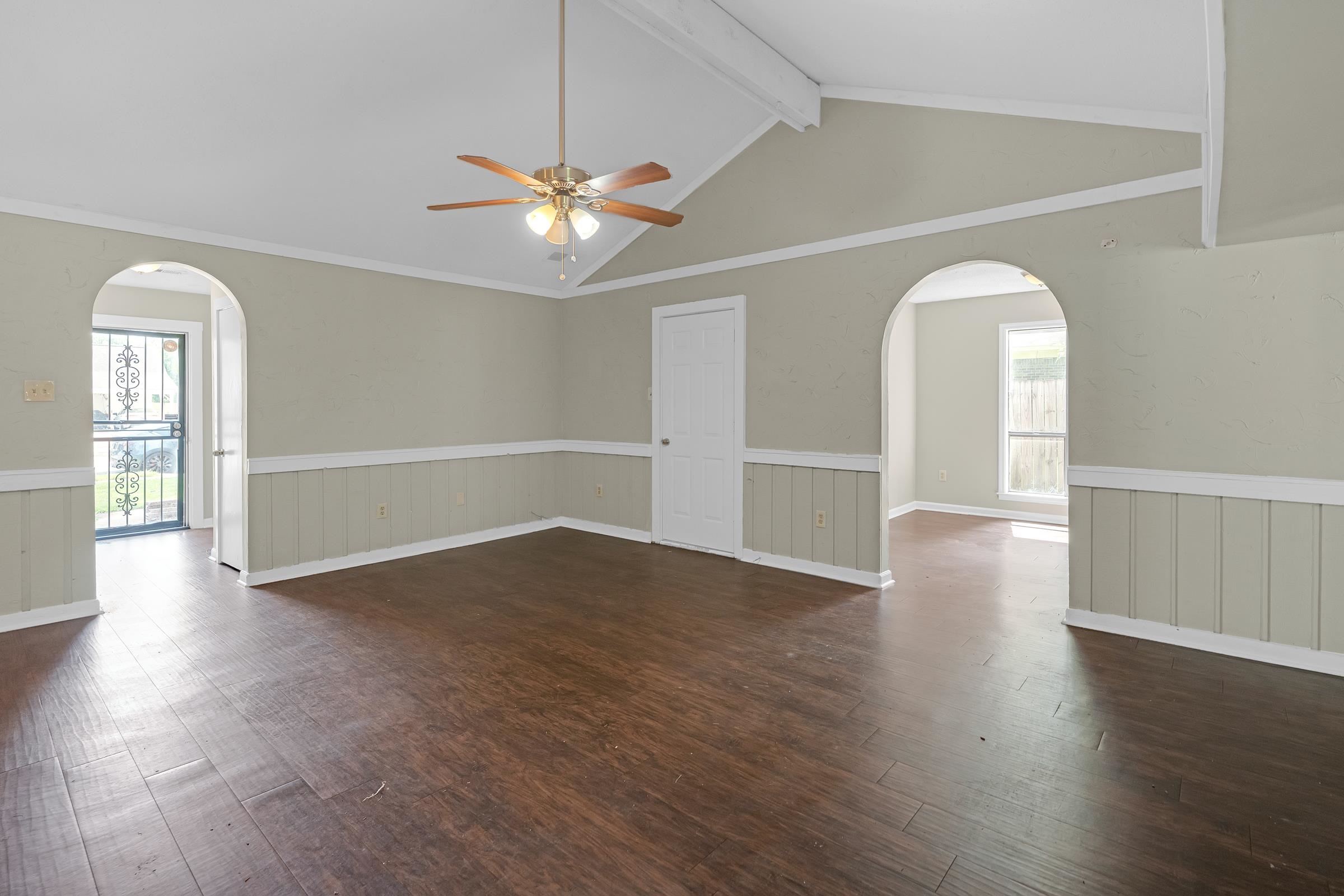 6128 Raintree Drive Memphis, TN 38115 - Photo 6 of 30 Unfurnished room featuring arched walkways, dark wood finished floors, beam ceiling, a wainscoted wall, and a ceiling fan