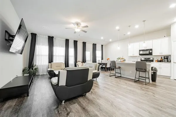 a living room with furniture kitchen view and a large window