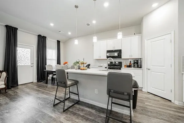 a kitchen with kitchen island granite countertop wooden floors and white cabinets