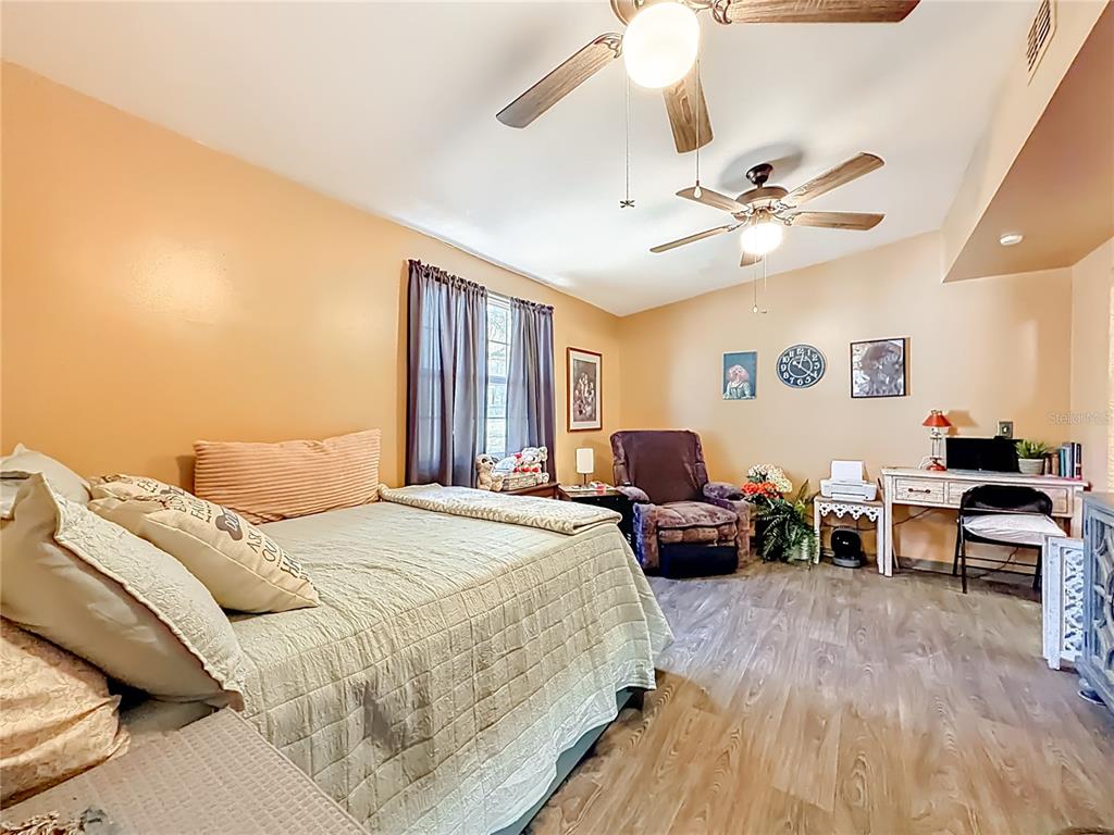 457 North Rooks Avenue Inverness, FL 34453 - Photo 29 of 61 a spacious bedroom with a bed a couch and a chandelier