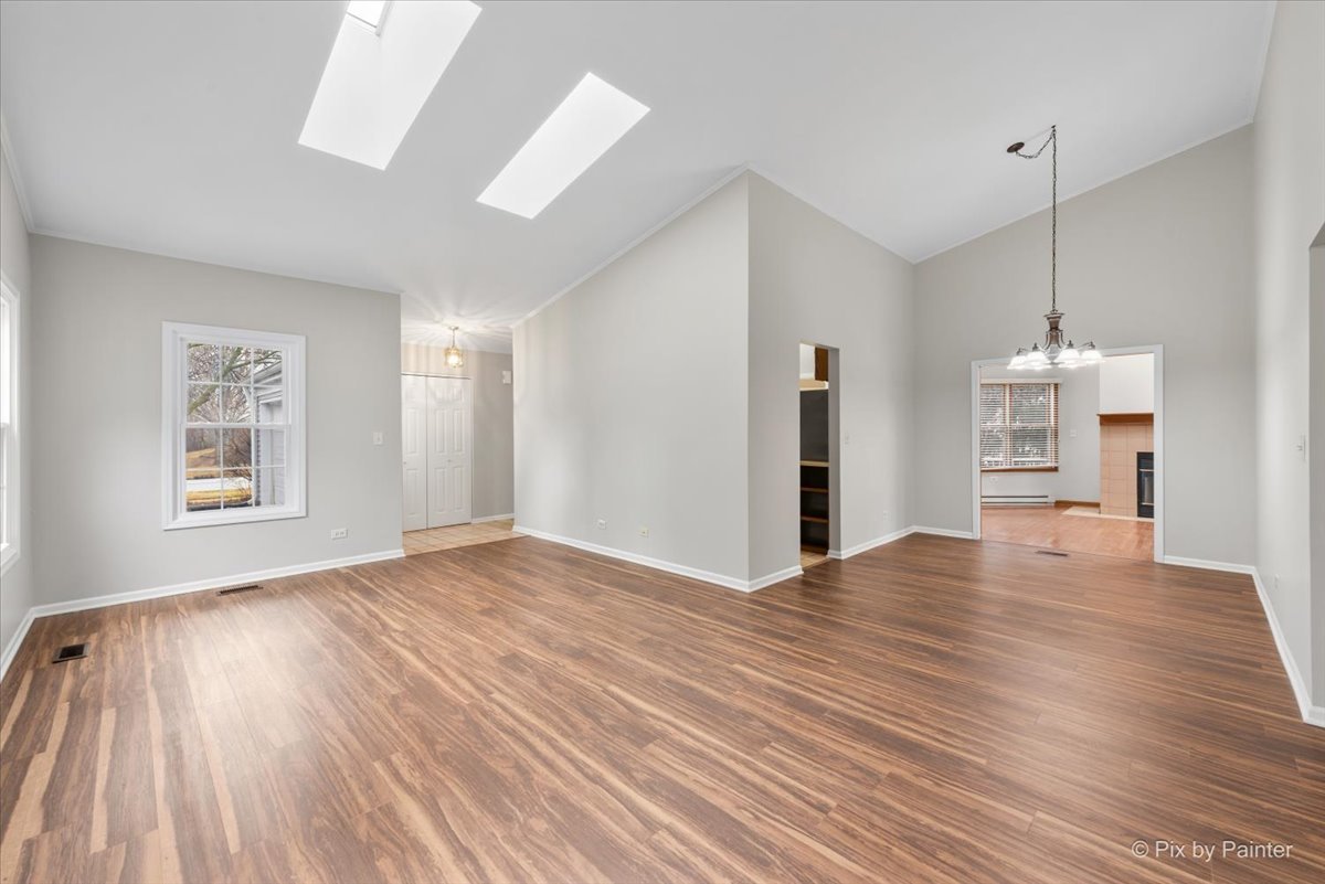 1095 Devonshire Avenue Naperville, IL 60540 - Photo 7 of 48 a view of empty room with wooden floor and kitchen view