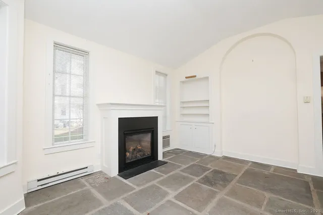 a view of an empty room with a fireplace and a window