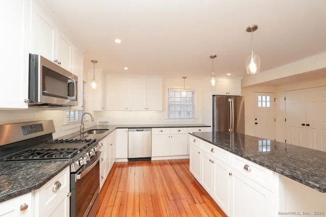 a large kitchen with stainless steel appliances granite countertop a stove and a sink