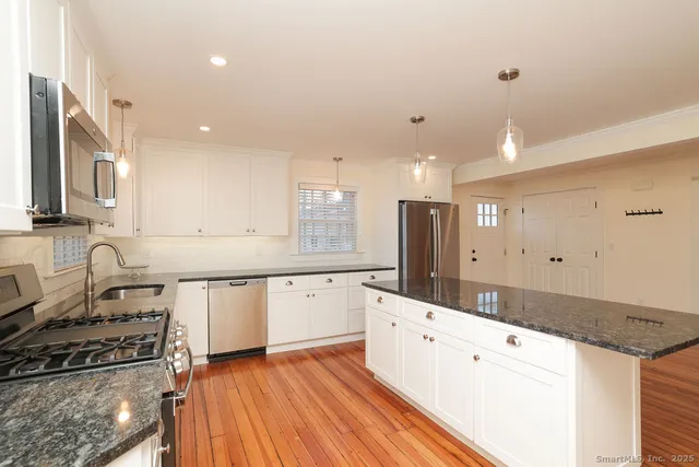 a kitchen with granite countertop a sink stove and cabinets
