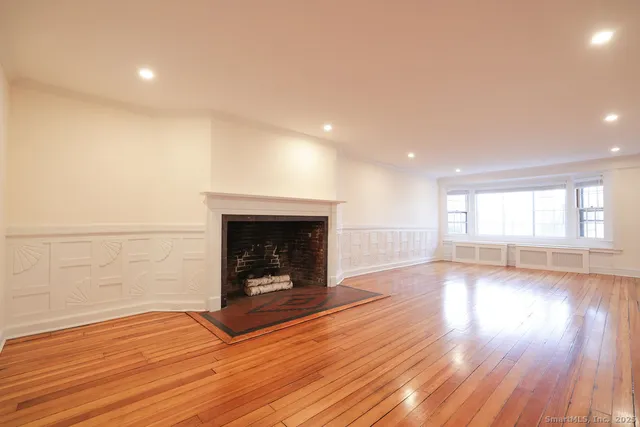 a view of empty room with wooden floor and fireplace