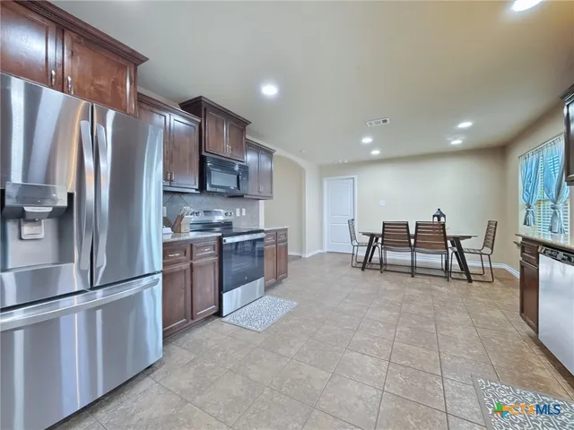 a kitchen with stainless steel appliances granite countertop a refrigerator and a stove top oven