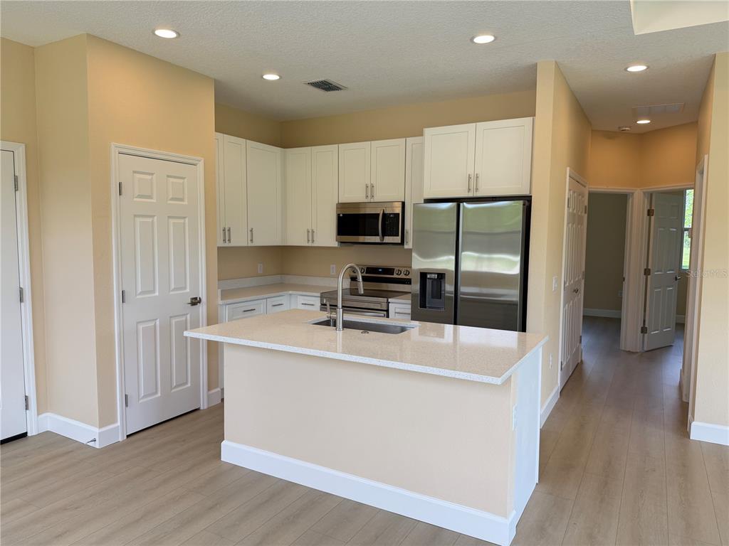 4661 Hickory Tree Road St. Cloud, FL 34772 - Photo 8 of 20 a large kitchen with stainless steel appliances a large counter top a stove a sink and a refrigerator