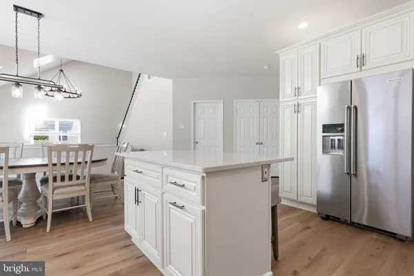 a dining room with stainless steel appliances granite countertop a dining table chairs stove and white cabinets