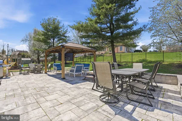 a view of a patio with a dining table and chairs under an umbrella with a barbeque grill and plants