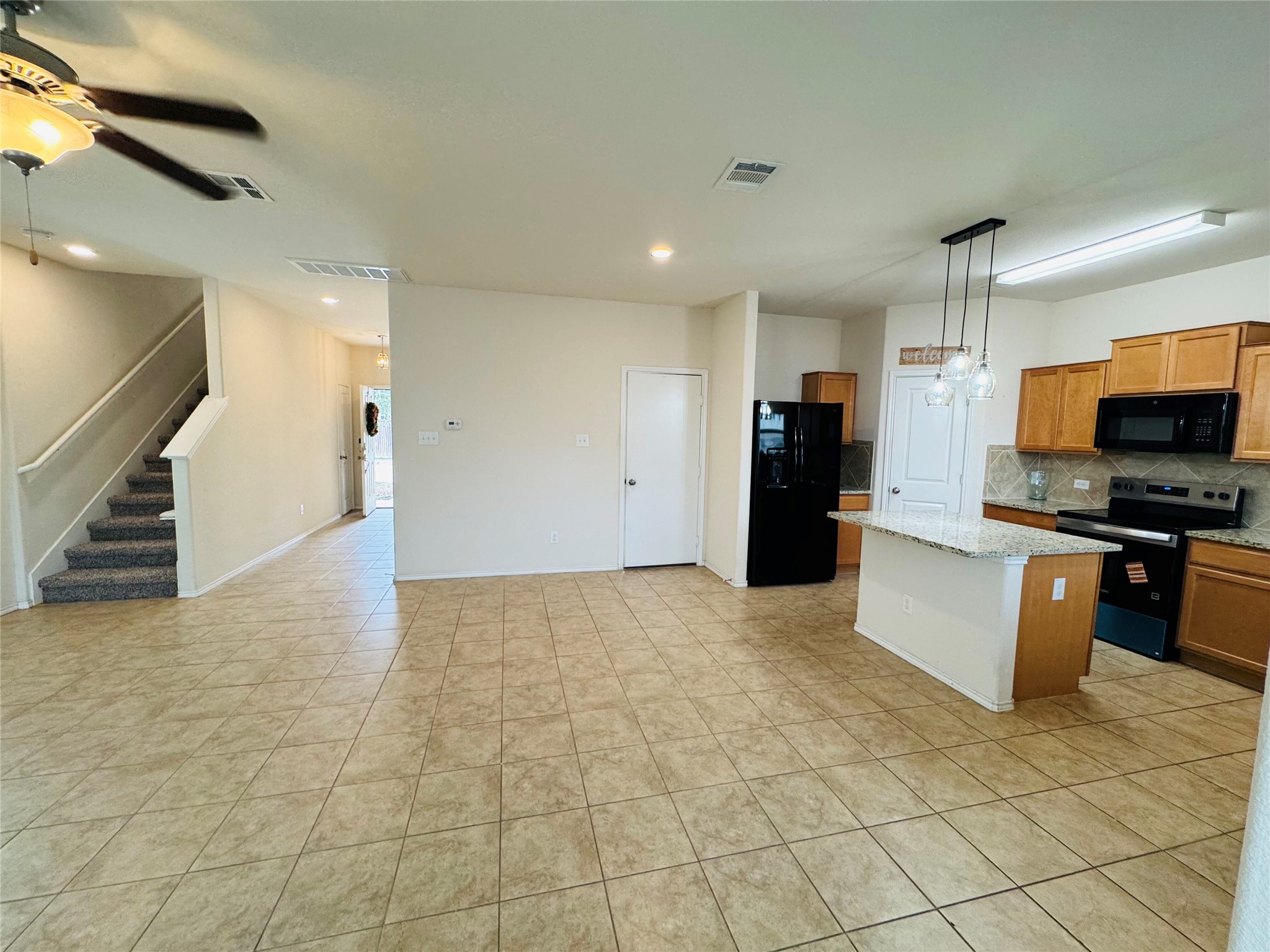 1108 Jackson Lane, Unit 5B Jarrell, TX 76537 - Photo 3 of 29 Kitchen featuring black appliances, a kitchen island, a ceiling fan, and wood finish cabinetry