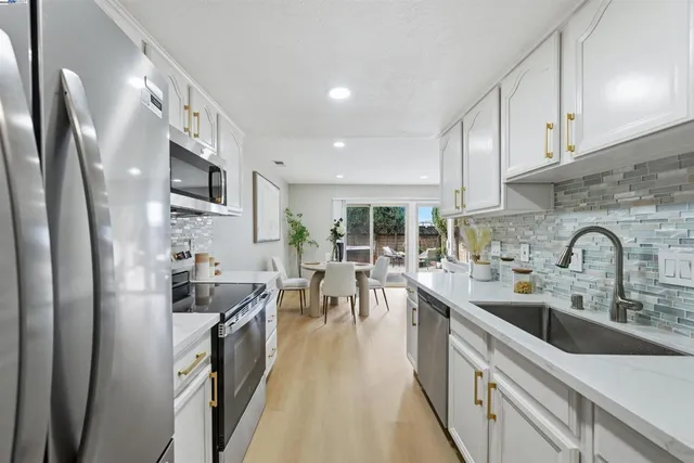 a kitchen with stainless steel appliances a refrigerator a sink a stove and white cabinets