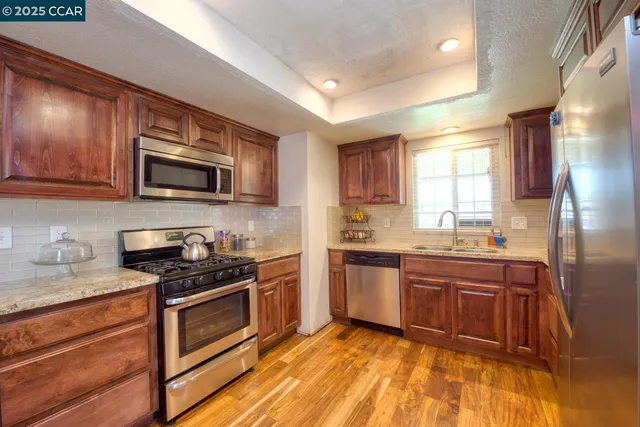 a kitchen with stainless steel appliances granite countertop wooden cabinets stove top oven and sink