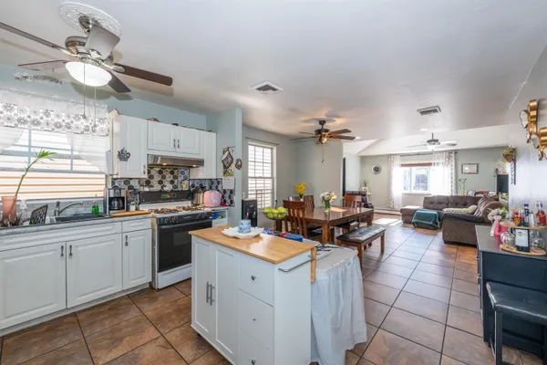 a open kitchen with stainless steel appliances kitchen island granite countertop a sink dishwasher stove and white cabinets