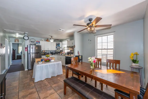 a room with stainless steel appliances kitchen island granite countertop a table chairs and a refrigerator