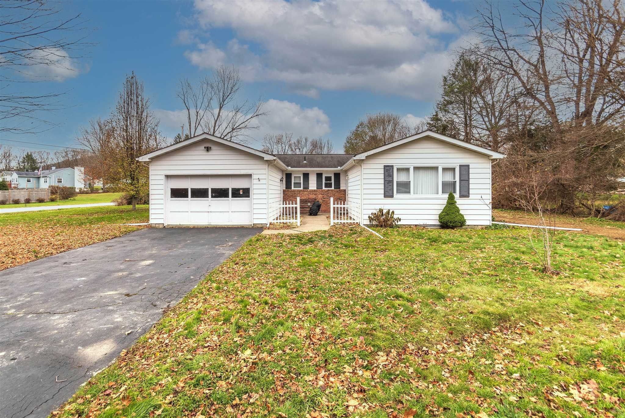 a front view of a house with a yard and large trees