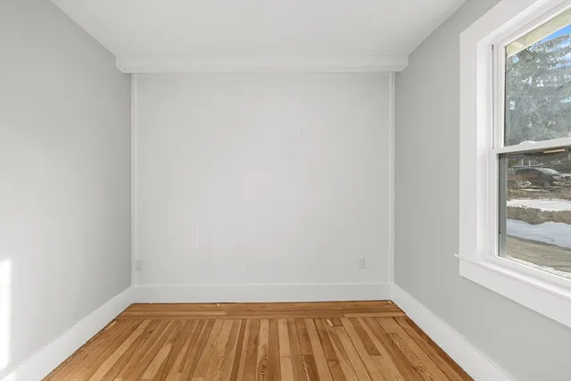 a view of a room with wooden floor and small window