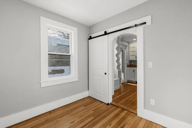 a view of hallway with wooden floor and a window