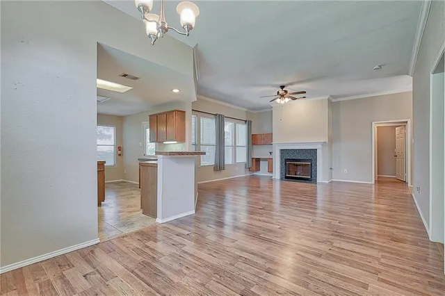 a view of a kitchen and an empty room with wooden floor