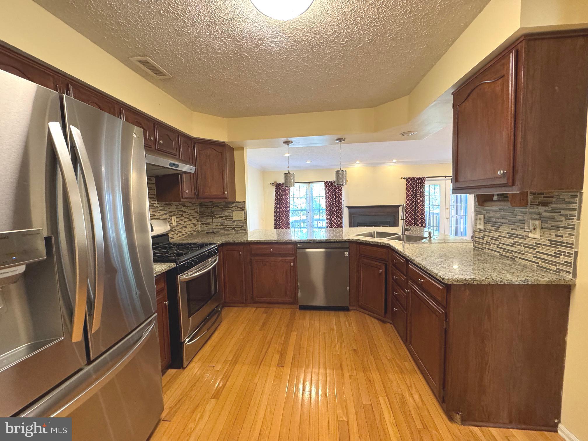 36 Castleton Road Princeton, NJ 08540 - Photo 3 of 5 a large kitchen with a stove a sink dishwasher a refrigerator and wooden cabinets with wooden floor