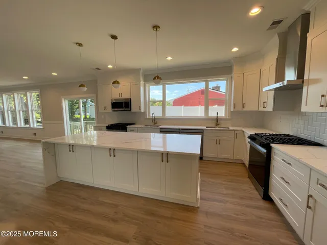 a kitchen with stainless steel appliances granite countertop a sink cabinets and wooden floor